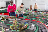 African and caucasian men playing with slot car racing