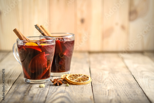 Mulled wine in glasses with apples, orange, cinnamon and star anise. Hot Christmas drink on a rustic background with copy space.