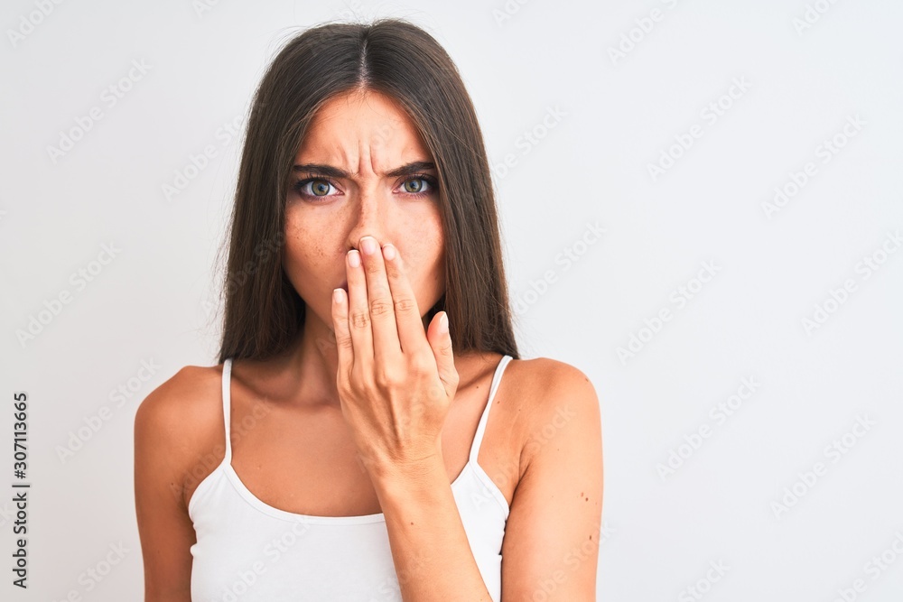 Young beautiful woman wearing casual t-shirt standing over isolated white background cover mouth with hand shocked with shame for mistake, expression of fear, scared in silence, secret concept Young beautiful woman wearing casual t-shirt standing over isolated white background cover mouth with hand shocked with shame for mistake, expression of fear, scared in silence, secret concept