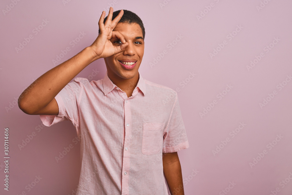Young handsome arab man wearing casual shirt standing over isolated pink background doing ok gesture with hand smiling, eye looking through fingers with happy face. Young handsome arab man wearing casual shirt standing over isolated pink background doing ok gesture with hand smiling, eye looking through fingers with happy face.