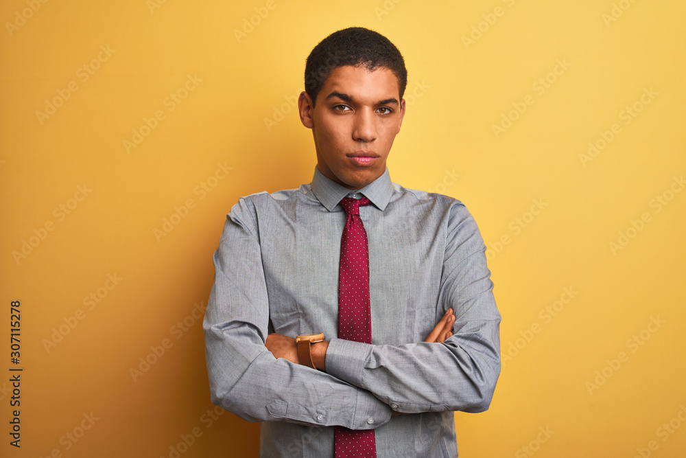 Young handsome arab businessman wearing shirt and tie over isolated yellow background skeptic and nervous, disapproving expression on face with crossed arms. Negative person. Young handsome arab businessman wearing shirt and tie over isolated yellow background skeptic and nervous, disapproving expression on face with crossed arms. Negative person.