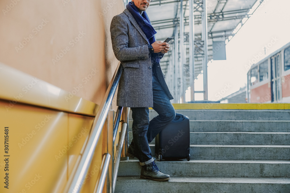 Elegant young man standing on steps and using cellphone Elegant young man standing on steps and using cellphone