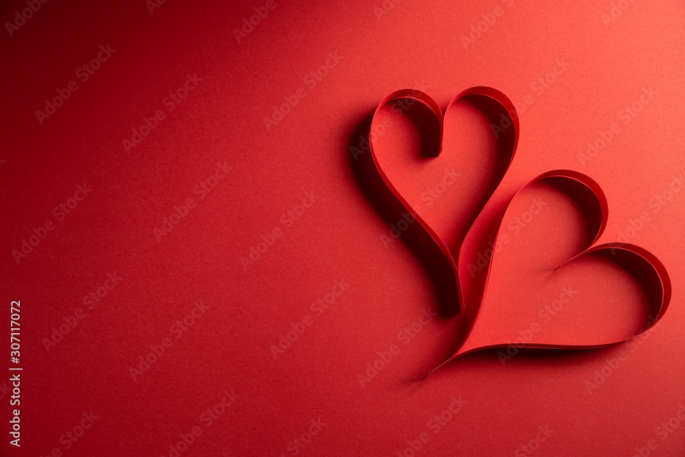 Two red paper hearts on red paper background. Love and Valentine's day concept.