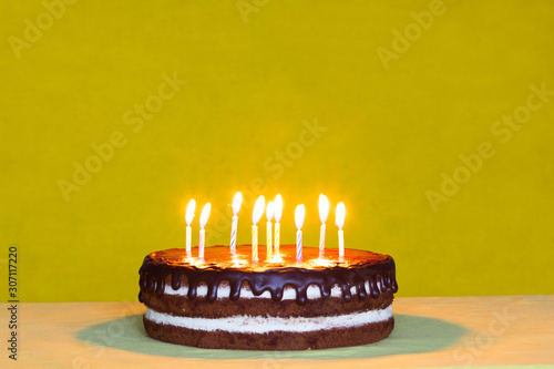 Canvas Print Chocolate cake with white cream and chocolate drops and candies on yellow backgr