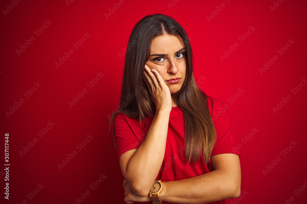 Young beautiful woman wearing t-shirt standing over isolated red background thinking looking tired and bored with depression problems with crossed arms. Young beautiful woman wearing t-shirt standing over isolated red background thinking looking tired and bored with depression problems with crossed arms.