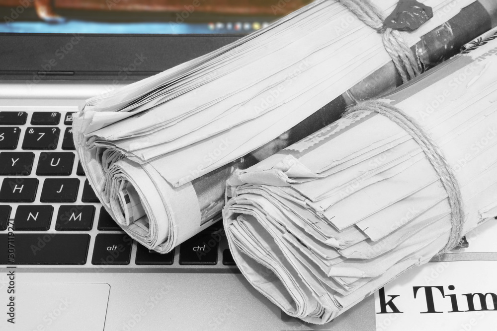 Newspapers Folded and Stacked on Computer Keyboard. Magazines and Open Laptop. News on Paper Pages or on Digital Screen. Business Concept Newspapers Folded and Stacked on Computer Keyboard. Magazines and Open Laptop. News on Paper Pages or on Digital Screen. Business Concept