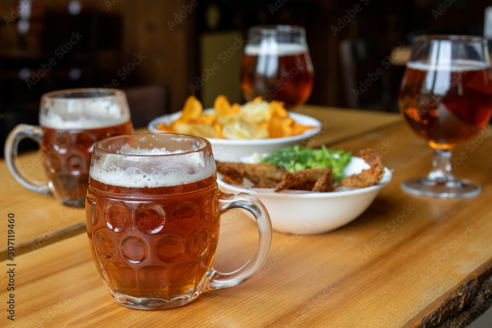 Mug with beer and beer snacks. Corn chips with sauce, fish and greens. Mug with beer and beer snacks. Corn chips with sauce, fish and greens.