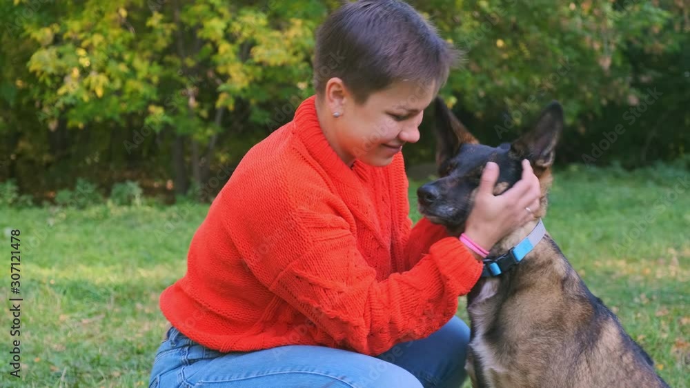 A young woman is playing with her dog in a park. She hugs her beloved pet A young woman is playing with her dog in a park. She hugs her beloved pet