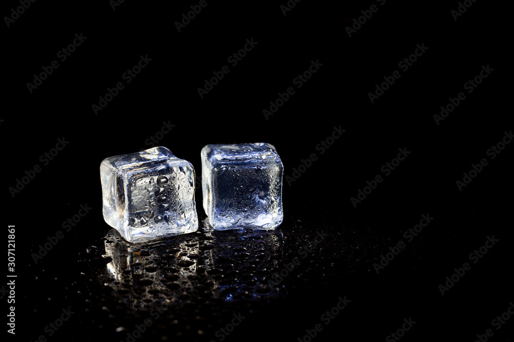 ice cubes reflection on black table background.