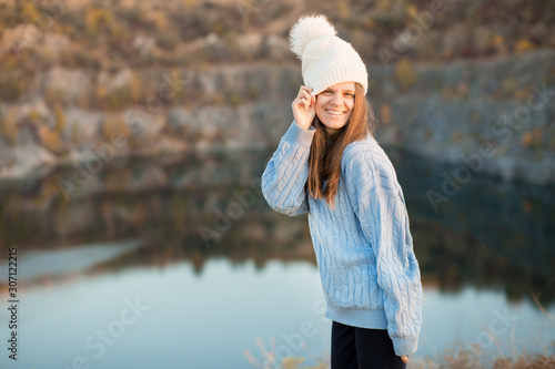 Winter portrait of smilling woman in white hat with big bubo makes funny face outdoor