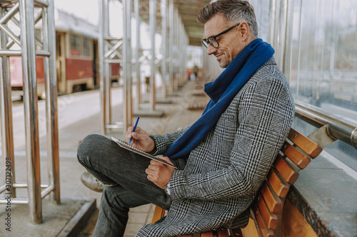 Handsome smiling man writing in notebook outdoors