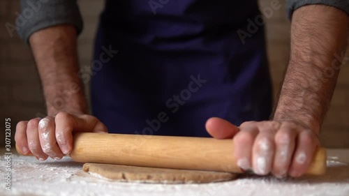 Male hands rolling out ginderbread dough cooking honey-cake at home