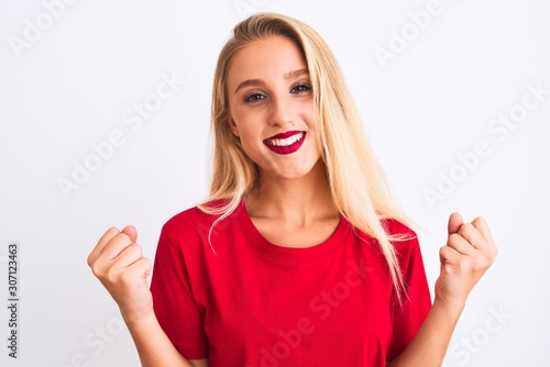 Young beautiful woman wearing red casual t-shirt standing over isolated white background celebrating surprised and amazed for success with arms raised and open eyes. Winner concept.