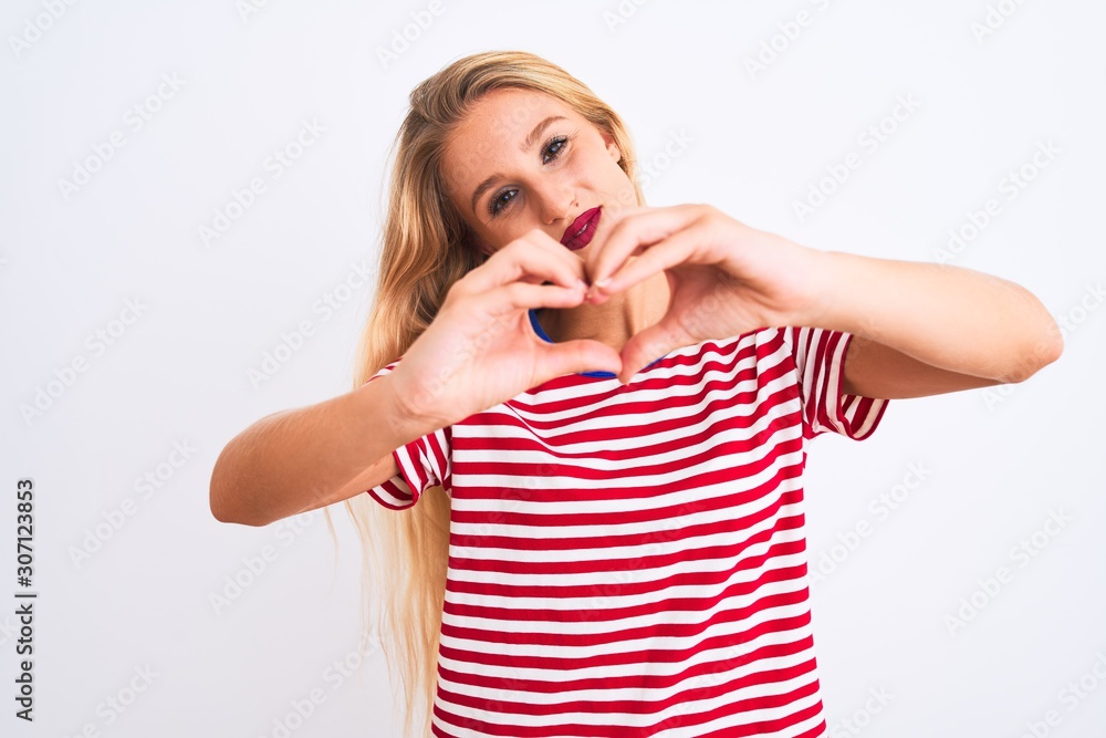 Young beautiful woman wearing red striped t-shirt standing over isolated white background smiling in love showing heart symbol and shape with hands. Romantic concept. Young beautiful woman wearing red striped t-shirt standing over isolated white background smiling in love showing heart symbol and shape with hands. Romantic concept.