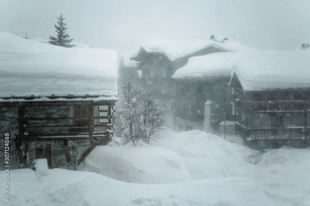 Heavy snow storm at Val d'Isere, Savoie of France. Buildings covered with snow during hard winter conditions on January at French Alps.	