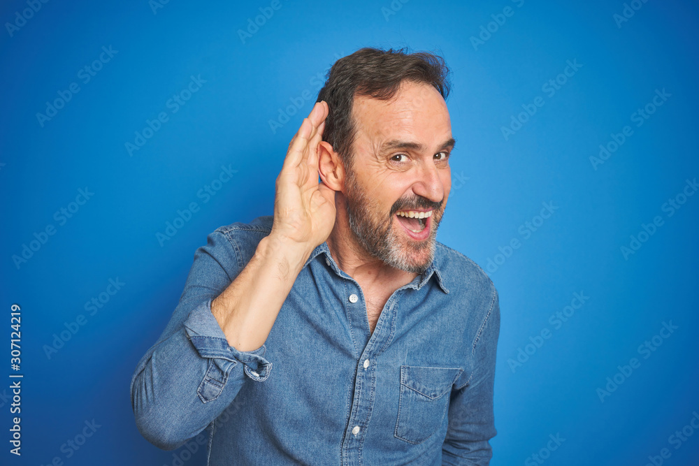 Handsome middle age senior man with grey hair over isolated blue background smiling with hand over ear listening an hearing to rumor or gossip. Deafness concept. Handsome middle age senior man with grey hair over isolated blue background smiling with hand over ear listening an hearing to rumor or gossip. Deafness concept.