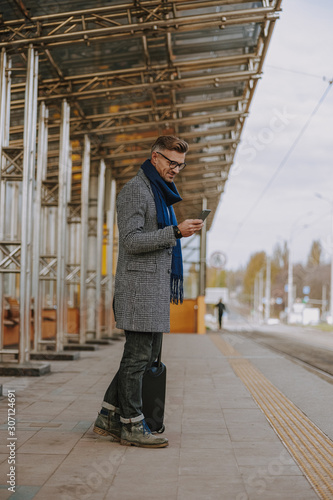Good-looking gentleman using smartphone on the street