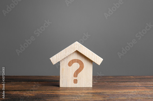 Question mark on a wooden house. Solving housing problems, deciding to buy or rent real estate. Search for options, the choice of accommodation between apartment and house. Cost estimate photo