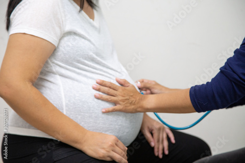Pregnant woman with a doctor at the hospital  Concept  Family expectations Happy lifestyle  mother in dress holds hands on belly Waiting for  birth of childbirth  Pregnant women touching the abdomen