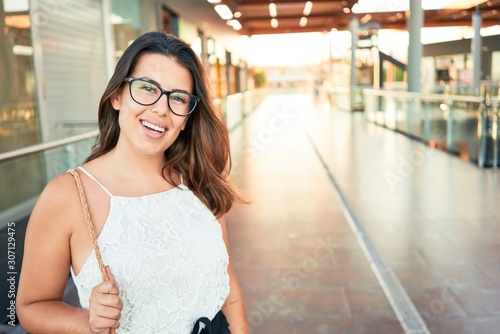 Young beautiful woman inside of shopping center, standing smiling happy and cheerful at the mall