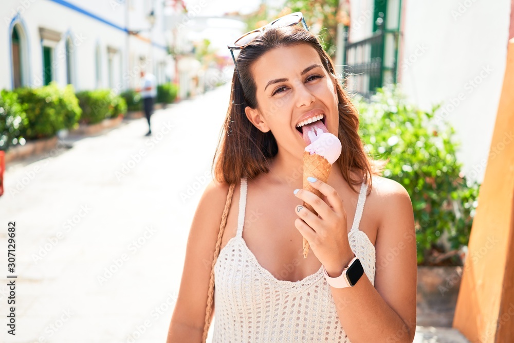 Fototapeta premium Young beautiful woman eating ice cream cone on a sunny day of summer on holidays