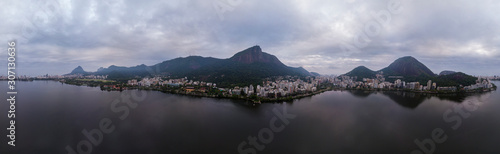 Aerial full 360 degrees panorama of the city lake in Rio de Janeiro on an overcast early morning with thick clouds over the Corcovado mountain and still dark landscape