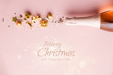 Flat lay of Celebration. Champagne bottle and golden decoration on pink background with text