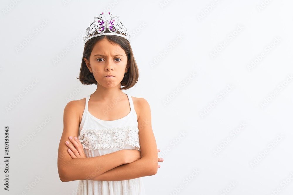 Beautiful child girl wearing princess crown standing over isolated white background skeptic and nervous, disapproving expression on face with crossed arms. Negative person. Beautiful child girl wearing princess crown standing over isolated white background skeptic and nervous, disapproving expression on face with crossed arms. Negative person.