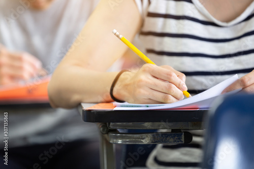 high school,university student study.hands holding pencil writing paper answer sheet.sitting lecture chair taking final exam attending in examination classroom.concept scholarship for education abroad