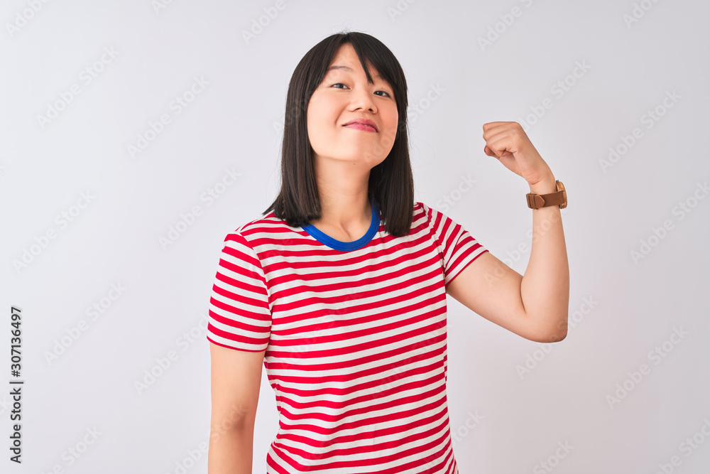 Young beautiful chinese woman wearing red striped t-shirt over isolated white background Strong person showing arm muscle, confident and proud of power Young beautiful chinese woman wearing red striped t-shirt over isolated white background Strong person showing arm muscle, confident and proud of power