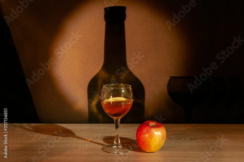 A slice of apple lies in a glass with calvados on the background of the bottle