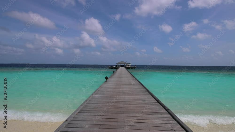 Walking on a long wooden pier with azure blue water around. Clouds in the sky in the Maldives. Stabilized forward engagement. Walking on a long wooden pier with azure blue water around. Clouds in the sky in the Maldives. Stabilized forward engagement.