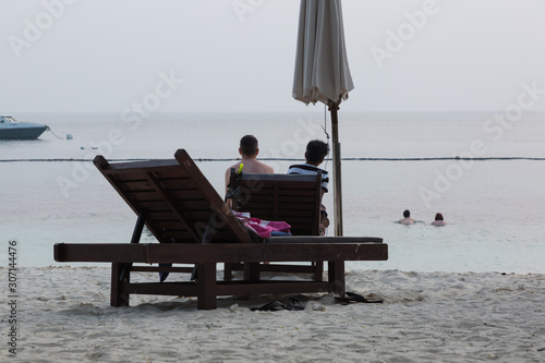 Couple sitting together on beach chair at perhentian islands in Terengganu in Malaysia photo