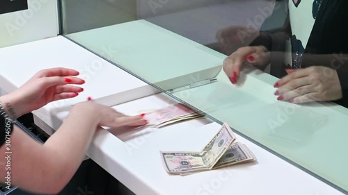 Employee and client count money on a counter at the currency exchange office. Female hand with money in cash department window. photo