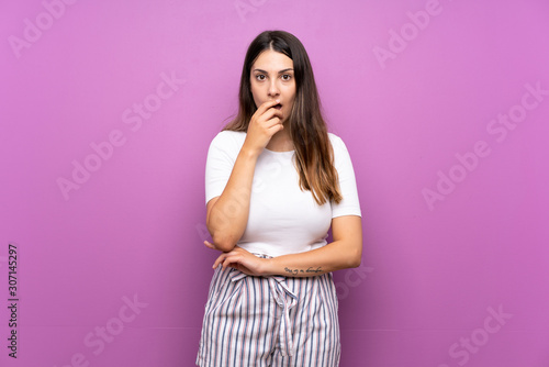 Young woman over isolated purple background surprised and shocked while looking right
