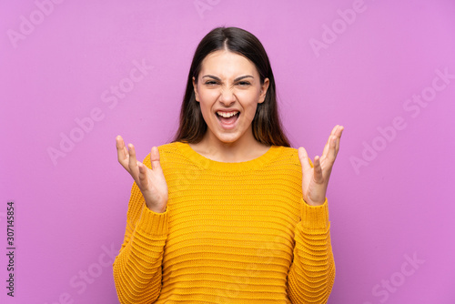 Young woman over isolated purple background unhappy and frustrated with something © luismolinero