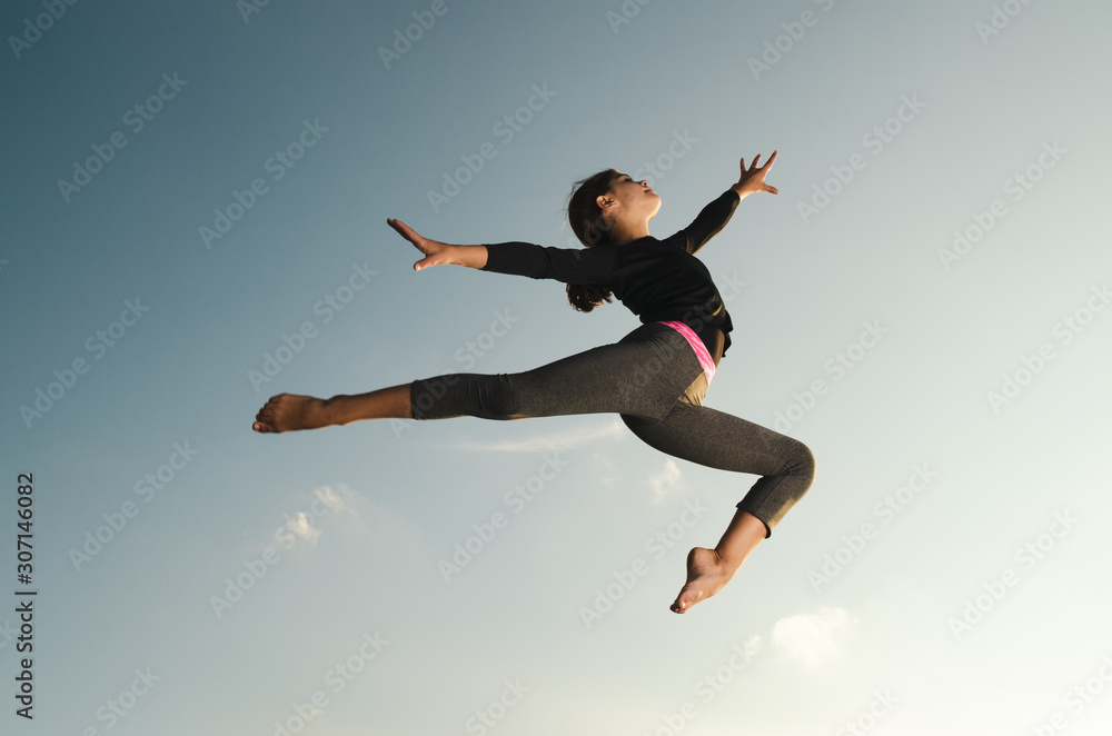 Young girl gymnast acrobat jumping high in the sky Young girl gymnast acrobat jumping high in the sky