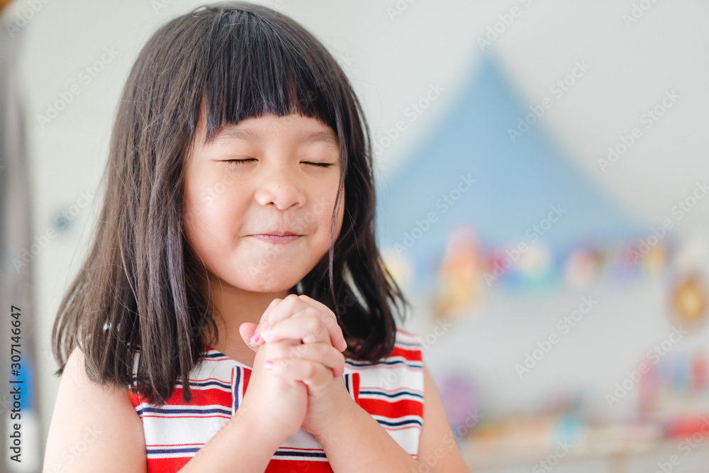 Asian Girl praying on birthday on the morning at home.Asian girl hand praying,Hands folded in prayer concept for faith,spirituality and religion. - obrazy, fototapety, plakaty 