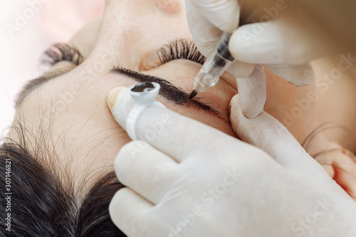 Permanent makeup, tattooing of eyebrows. Cosmetologist applying make up