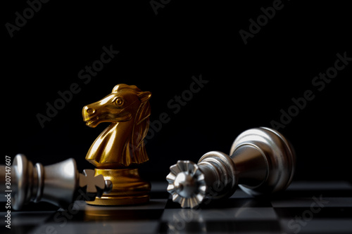 Golden knight stand as last winner over silver king on chess board. Black background for Bankruptcy concept.