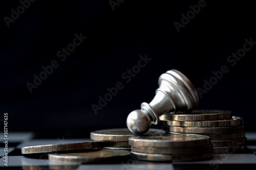 Chess fall down on pile of coins. Dark color tone for business difficulties and bankruptcy concept.