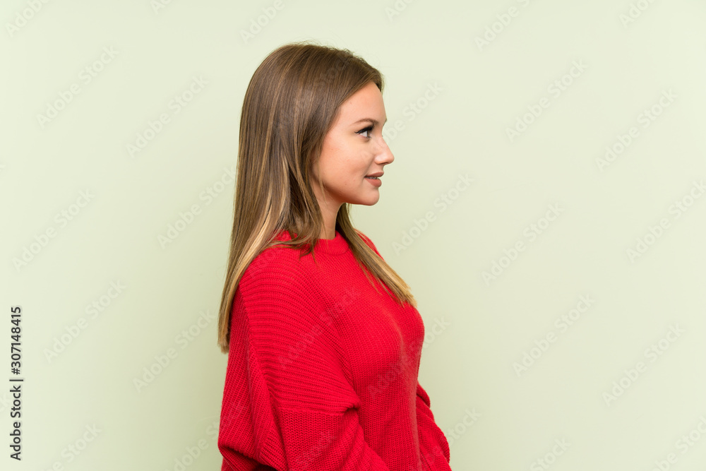 Teenager girl over isolated green background looking to the side Teenager girl over isolated green background looking to the side