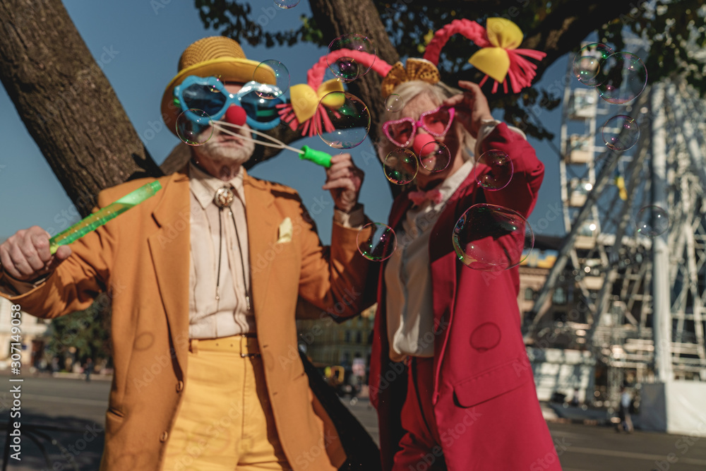 Fototapeta premium Jolly elderly couple in clown clothes outdoors stock photo