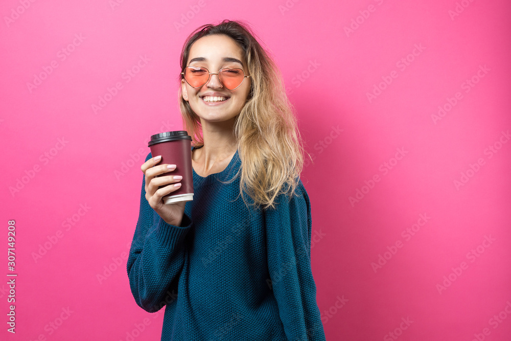 Glamor woman in glasses in a blue sweater with a drink of coffee on a pink background. Glamor woman in glasses in a blue sweater with a drink of coffee on a pink background.
