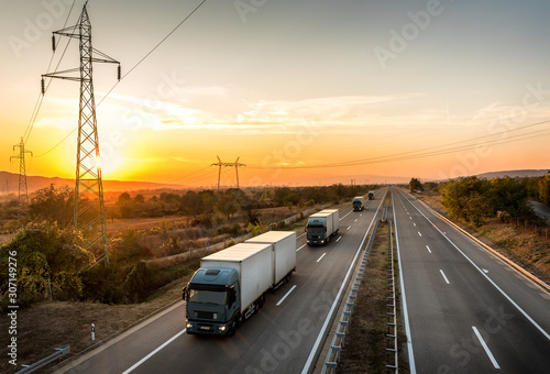 Convoy of five blue lorry trucks on a highway. Highway transportation with blue lorry tracks convoy