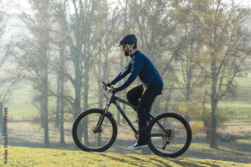 Cyclist in pants and fleece jacket on a modern carbon hardtail bike with an air suspension fork. The guy on the top of the hill rides a bike. Cyclist in pants and fleece jacket on a modern carbon hardtail bike with an air suspension fork. The guy on the top of the hill rides a bike.