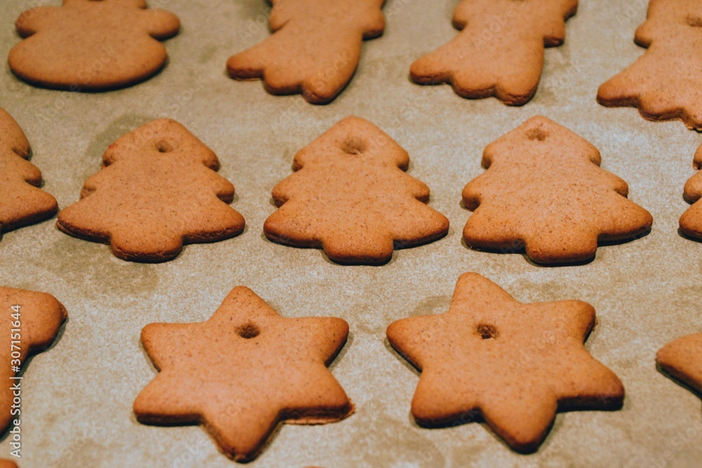 Christmas cookies. Homemade gingerbread cookies in various shapes on the baking tray. Cookies freshly made at home, golden browned colored cookies before decorating with icing Christmas cookies. Homemade gingerbread cookies in various shapes on the baking tray. Cookies freshly made at home, golden browned colored cookies before decorating with icing