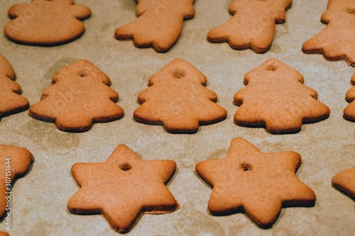 Christmas cookies. Homemade gingerbread cookies in various shapes  on the baking tray. Cookies freshly made at home, golden browned colored cookies before decorating with icing