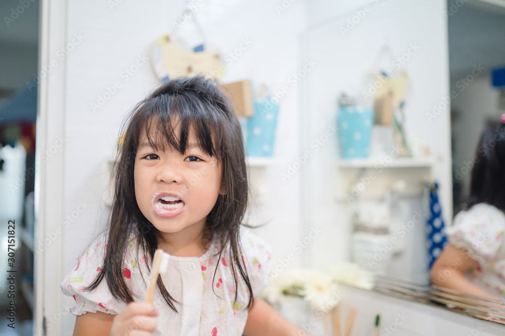 5.5 years old little asian girl teeth brushing with bamboo toothbrush.child girl smiling while brushing her teeth.brushing teeth, healthy oral care, zero wast and plastic free concept.copy space. 5.5 years old little asian girl teeth brushing with bamboo toothbrush.child girl smiling while brushing her teeth.brushing teeth, healthy oral care, zero wast and plastic free concept.copy space.