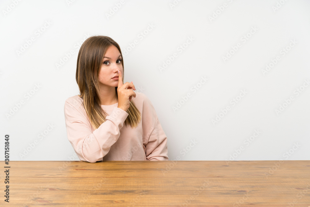Teenager girl in a table doing silence gesture Teenager girl in a table doing silence gesture